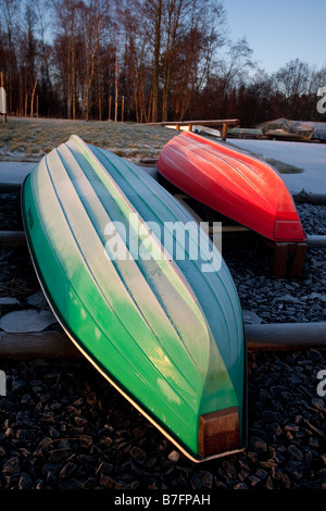 Rote und grüne umgedrehte Fiberglas Ruderboote, Skiffe, Skiffs / Dinghy / Schlauchboote im Winter , Finnland befahren Stockfoto