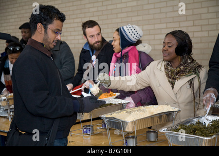 Freiwillige dienen Essen an die Obdachlosen in Outdoor-Suppenküche Stockfoto
