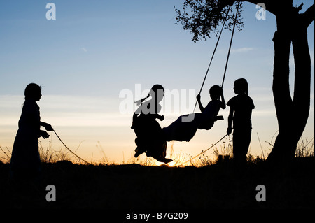 Silhouette der indischen Mädchen schwingen und Springen in den ländlichen indischen Landschaft bei Sonnenuntergang. Andhra Pradesh, Indien Stockfoto