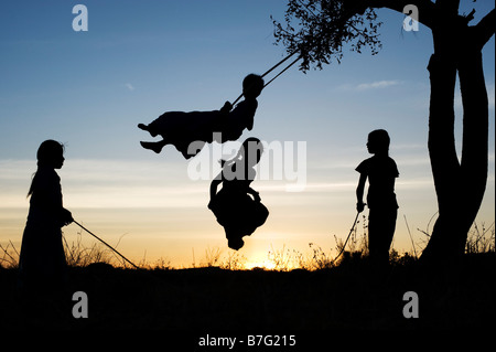 Silhouette der indischen Mädchen schwingen und Springen in den ländlichen indischen Landschaft bei Sonnenuntergang. Andhra Pradesh, Indien Stockfoto