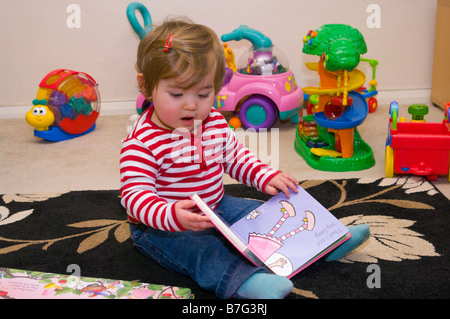 Baby Mädchen betrachten und lesen Sie ein Buch Stockfoto
