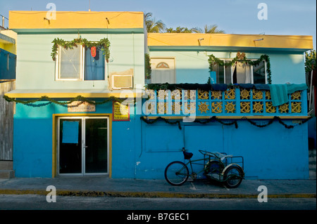 Parken drei zweirädrigen Karren, auf dem Bürgersteig vor einem blauen festliche Gebäude im Dezember auf der Isla Mujeres, Mexiko. Stockfoto