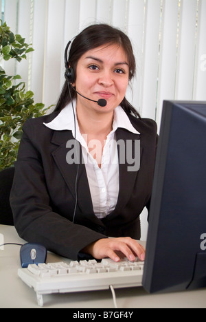 Eine junge Frau trägt ein Kopfhörer sitzt vor einem Computer-monitor Stockfoto