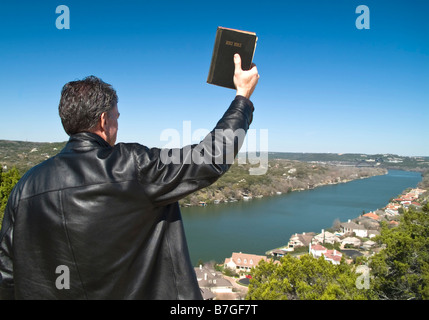 Ein Mann hält eine Bibel in seiner erhobenen Hand nach unten in einem wohlhabenden Viertel Stockfoto