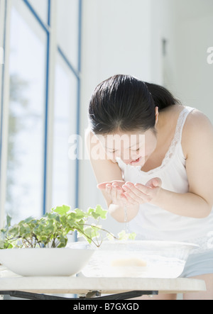Waschen Sie ihr Gesicht in Spüle Frau Stockfoto