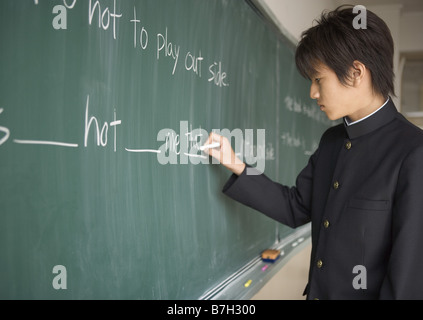 Schüler an Tafel schreiben Stockfoto