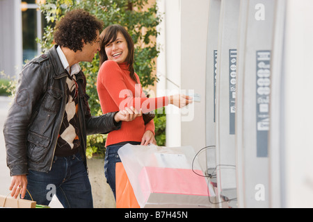 Paar mit Einkaufstüten an Geldautomaten Stockfoto