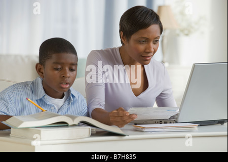 Afrikanischen jungen machen Hausaufgaben nächsten Mutter auf computer Stockfoto