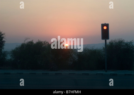 Sonnenuntergang mit roten Ampel auf der Straße in der Nähe von Larnaca Salt Lake und Hala Sultan Tekkesi Moschee Stockfoto