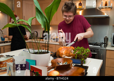 Junges Paar Vorbereitung Weihnachten oder Thanksgiving Abendessen Gegrillter Truthahn wird in modernen Wohnung geschnitzt Stockfoto