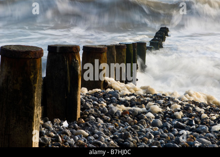 Wellen in und über Kies und Buhnen an der North Norfolk-Küste in der Nähe von Cromer, England UK verschwommen. Stockfoto
