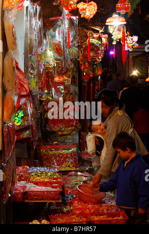 Chinesische Frau und Kinder Süßigkeiten für das chinesische Neujahr bei kleinen typischen Händler kaufen Stockfoto