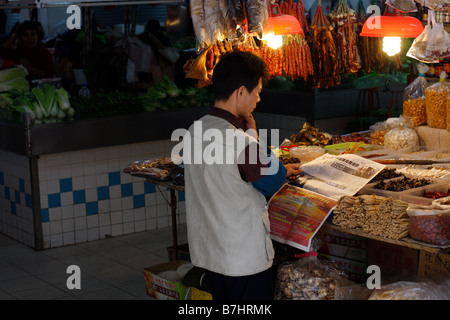 Chinesische Ladenbesitzer lesen Nachrichten im lokalen Markt Durring Vogelgrippe-Ausbruch Stockfoto