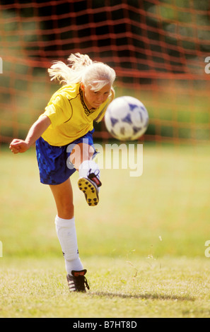 Ein zwölf Jahres altes Mädchen mit großer Konzentration kickt einen Fußball Stockfoto