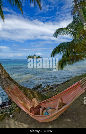 Eine Frau entspannt in einer Hängematte auf Isla Pelikano, San Blas Inseln, Kuna Yala, Panama Stockfoto