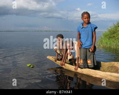 Drei glückliche junge Kinder in einem Einbaum-Kanu auf den Kongo-Fluss mit einem Spielzeug spielen Floß demokratische Republik Kongo Stockfoto