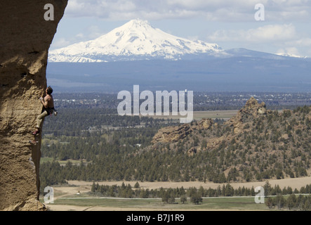 Mann (25-30) klettern mit Berg im Hintergrund, Smith Rock State Park, Oregon, USA Stockfoto