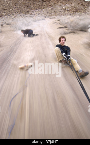 Zwei Männer (20-30) Surfen hinter einem Auto auf einem Feldweg, Bischof, Kalifornien, USA Stockfoto