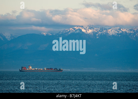 Containerschiff vor schneebedeckten Bergen, Victoria, BC, Kanada Stockfoto