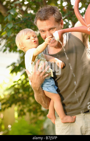 Papa & Baby spielt mit Gießkanne, Regina, Saskatchewan Stockfoto