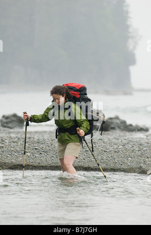 Frau (20-25) über einem schnell fließenden Bach mit einem großen Rucksack auf, West Coast Trail, Pacific Rim National Park Reserve, BC Stockfoto