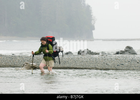 Frau (20-25) über einem schnell fließenden Bach mit einem großen Rucksack auf, West Coast Trail, Pacific Rim National Park Reserve, BC Stockfoto