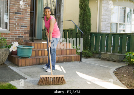 Afroamerikanische Frau fegen ihren Bürgersteig, Vancouver, BC Stockfoto