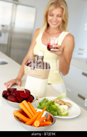 Mitte Erwachsene Frau macht frischen Gemüsesaft Stockfoto