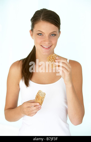 Junge Frau ein dunkles Brot Brötchen essen Stockfoto