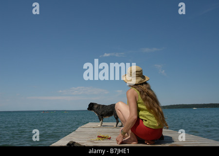 Frau und Hund auf Dock, Clear Lake; Kanada, Manitoba, Riding Mountain National Park Stockfoto