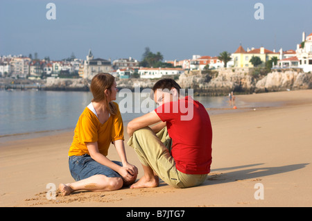 Junge romantisch zu zweit sitzen und reden am Sandstrand Stockfoto
