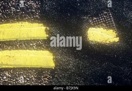 Detail von oben hell gelb Doppellinien festgelegten zweimal mit Patch von Asphalt liegend über kleinen Metallabdeckung GAS Stockfoto