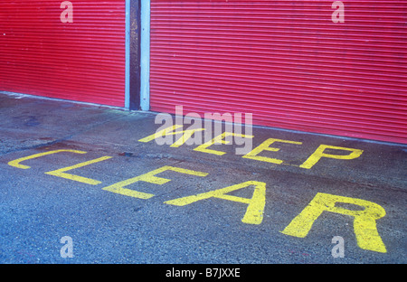 Roten Rolltore mit blauen und schwarzen Einfassung mit Betonfläche vorne mit Unterricht in gelb halten klar lackiert Stockfoto