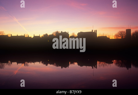 Magenta Sonnenuntergang Himmel spiegelt sich im Fluss mit Streifen der Stadtentwicklung in-between Silhouette Stockfoto