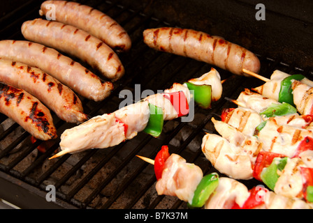 Würstchen und Hähnchenspieße auf einem Grill Stockfoto