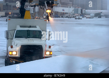 Die Bodenbesatzung des Flughafens spritzt Enteisungsflüssigkeit auf den Flugzeugflügel, um Schnee und Eis vor dem Start im Winter zu entfernen Stockfoto