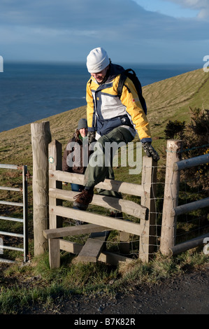 Zwei Menschen, die zu Fuß entlang der Ceredigion Küste kreuzen eine hölzernen Stil West Wales UK Stockfoto