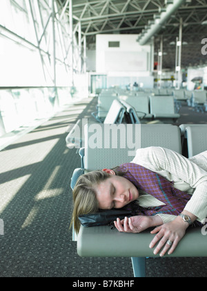 Frau schläft auf Bank im Flughafen Stockfoto