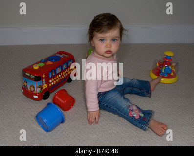 Ein kleines Mädchen, umgeben von ihrem Spielzeug Stockfoto