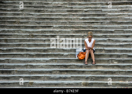 Frau sitzt auf den Stufen des Rathauses in Cortona Stockfoto