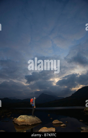 Wanderer auf Felsen in einem See stehen. Stockfoto