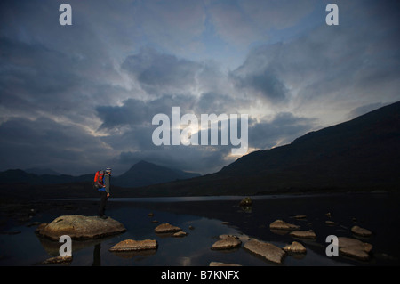 Wanderer auf Felsen in einem See stehen. Stockfoto