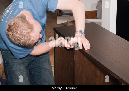 Tausendjährige junger Mann Montage einen Flachbild-pack Holzregal zu Hause. England Großbritannien Großbritannien Stockfoto