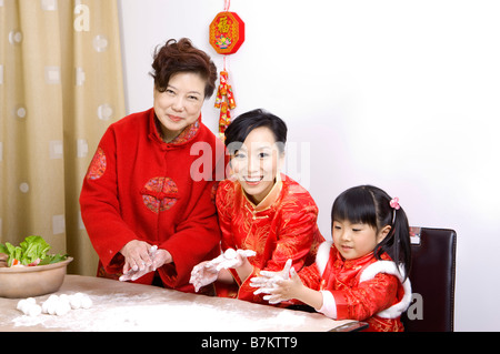 Drei-Generationen-Familie in traditioneller Kleidung, Knödel zusammen Stockfoto