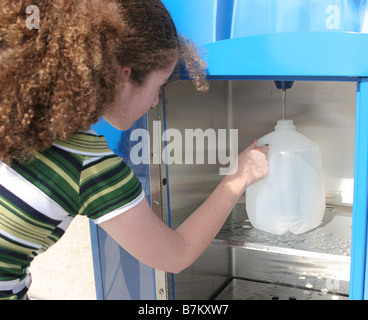 Eine teenie Girl füllen eine Flasche Wasser am Automaten in der Vorbereitung für einen Hurrikan könnte auch verwendet werden, für das recycling Stockfoto