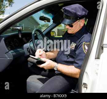 Polizist in seinem Streifenwagen ein Zitat ausfüllen Stockfoto