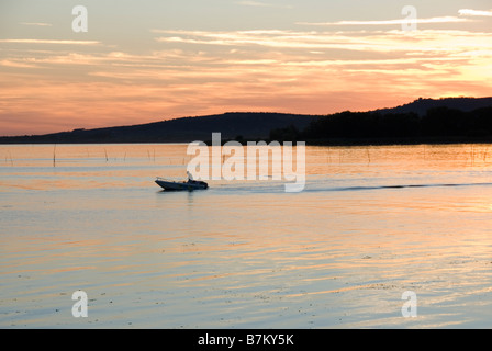 Ein Fischer kehrt nach Hause zurück bei Sonnenuntergang am Lago Trasimeno, Umbrien Italien Stockfoto