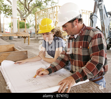 Ein Ingenieur und eine Studentin geht über Baupläne auf einer Baustelle Stockfoto