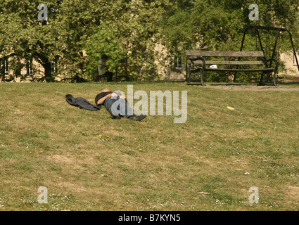 Betrunken [?] Mann schläft es sich im Park an einem heißen Sommertag Stockfoto