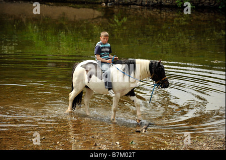 Ein Roma-junge reitet auf einem Pferd in den Fluss Eden in Appleby in Westmoreland Appleby Zigeuner Pferd Messe bareback Stockfoto